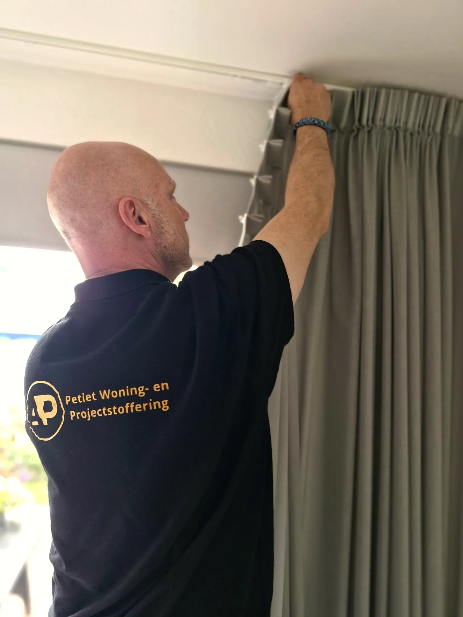 Allard Petiet hangt raamdecoratie/gordijnen op bij een klant